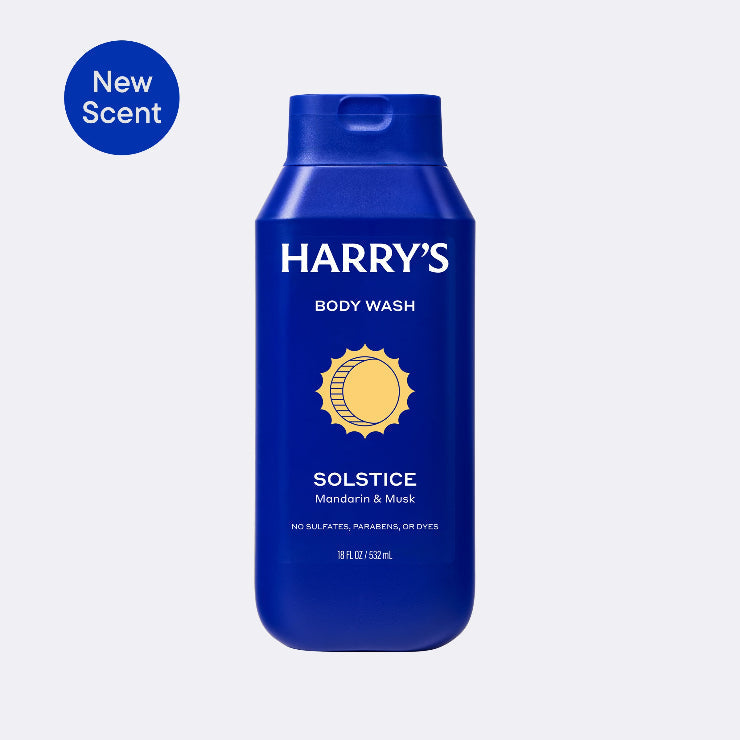 Blue bottle of Harry's Solstice body wash with 'New Scent' label on a light gray background