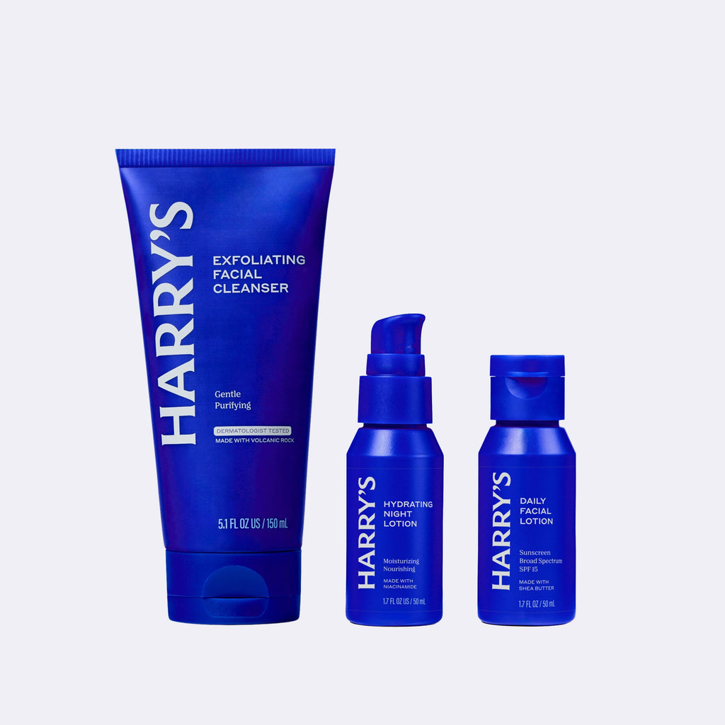 Three blue bottles of Harry's skincare products on a white background