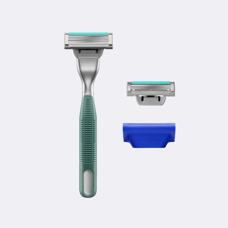 Harry's Plus Razor in the color Moss next to an extra blade cartridge and the blade cover on a white background.